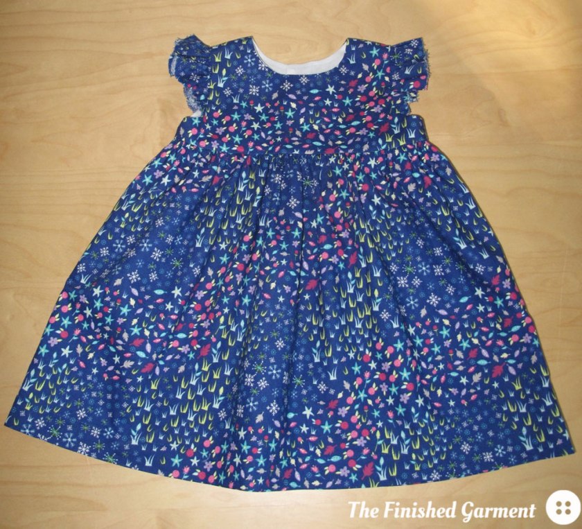 Baby dress made by The Finished Garment using the Geranium Dress sewing pattern from Made by Rae and Floral Meadow fabric from the Storybook Lane collection.